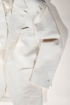 Close-up of a textured white blazer with a light background