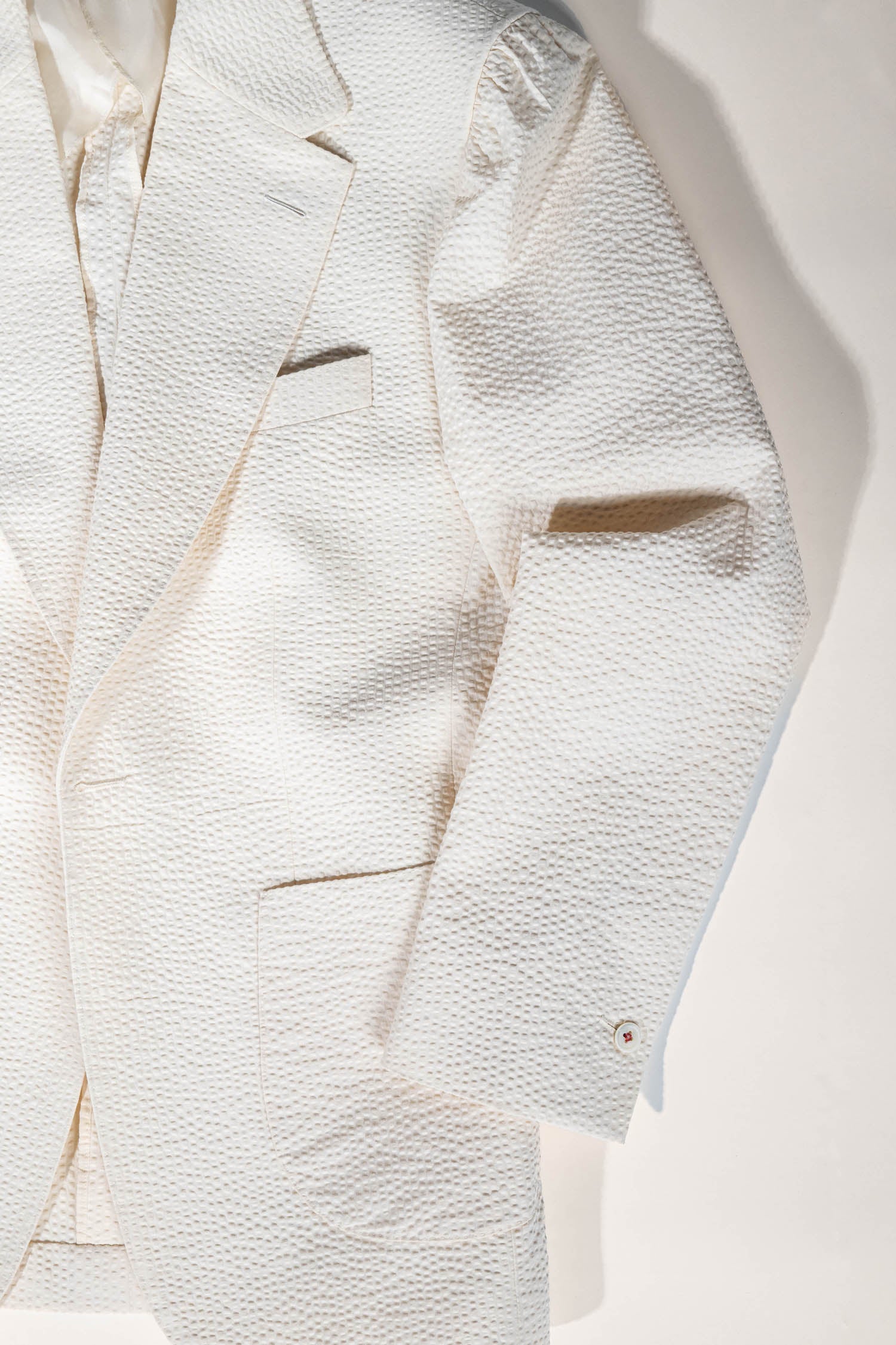 Close-up of a textured white blazer with a light background